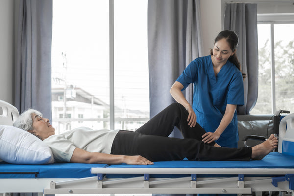 Physiotherapist assisting a patient on a hospital bed