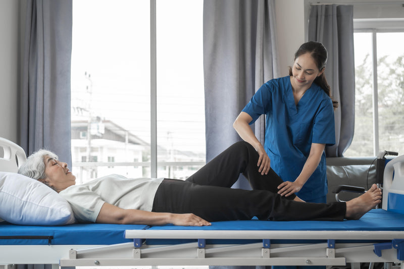 Physiotherapist assisting a patient on a hospital bed